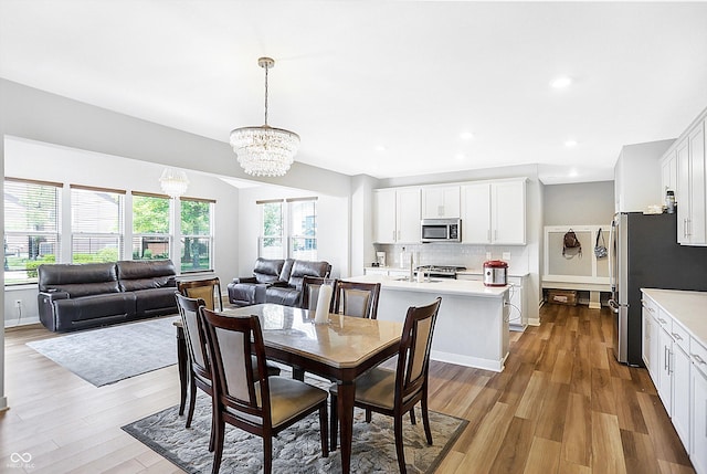 dining room with sink, a wealth of natural light, a chandelier, and light wood-type flooring