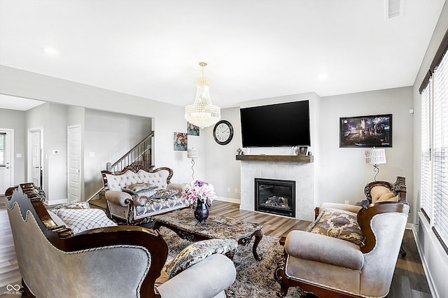 living room featuring a tiled fireplace, wood-type flooring, and a chandelier