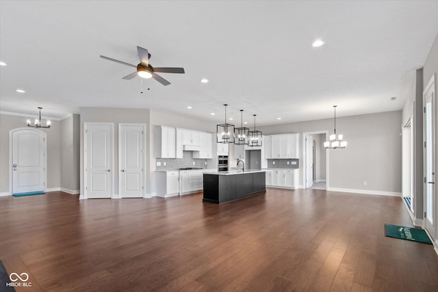 kitchen with white cabinetry, hanging light fixtures, tasteful backsplash, an island with sink, and dark hardwood / wood-style flooring