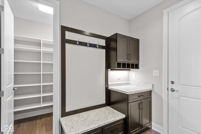 kitchen with light stone counters, dark hardwood / wood-style flooring, and dark brown cabinets