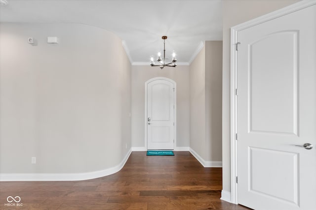 foyer entrance featuring an inviting chandelier, ornamental molding, and dark hardwood / wood-style flooring