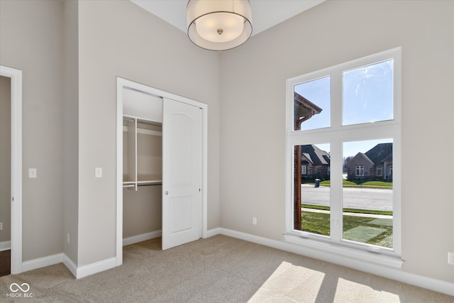 unfurnished bedroom with light colored carpet and a closet