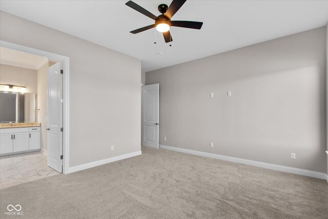 unfurnished bedroom with connected bathroom, sink, light colored carpet, and ceiling fan