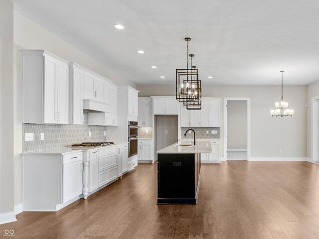 kitchen featuring white cabinetry, pendant lighting, and a kitchen island with sink