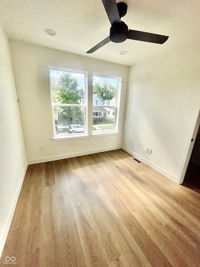 unfurnished room featuring ceiling fan, light hardwood / wood-style flooring, and a healthy amount of sunlight