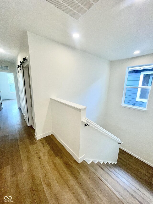 staircase with a barn door and wood-type flooring