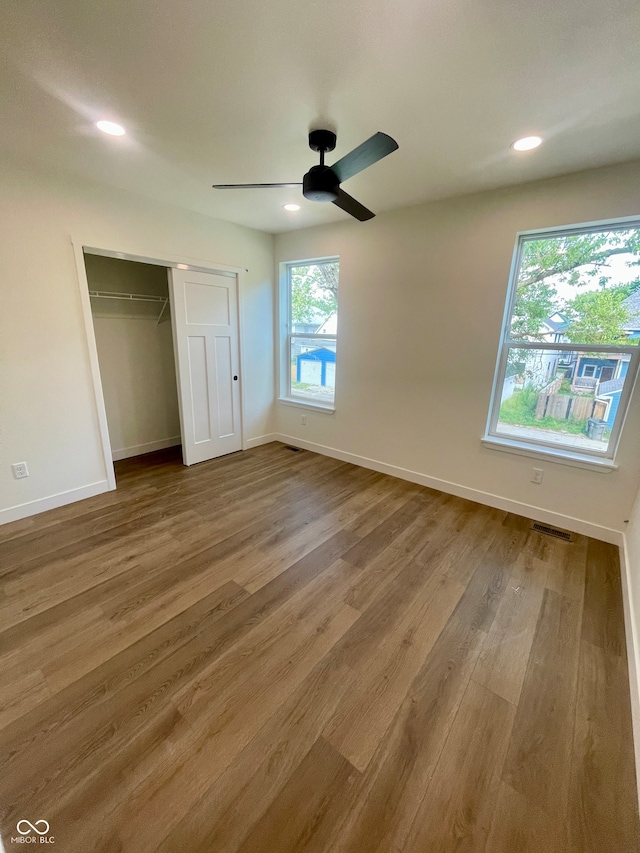 unfurnished bedroom featuring hardwood / wood-style floors, a closet, and ceiling fan