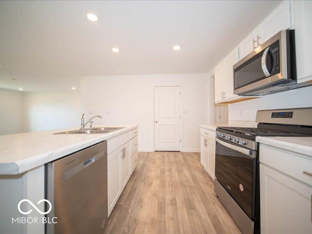 kitchen featuring sink, white cabinets, stainless steel appliances, and light wood-type flooring