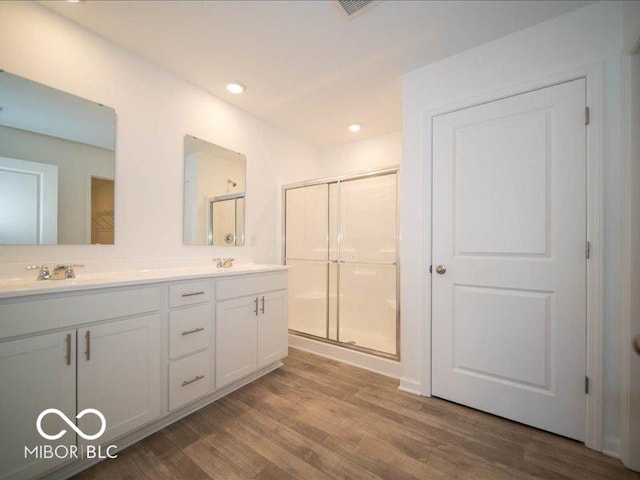 bathroom featuring wood-type flooring, vanity, and a shower with door