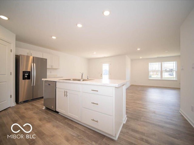 kitchen featuring white cabinetry, hardwood / wood-style floors, an island with sink, and appliances with stainless steel finishes