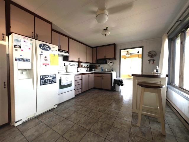 kitchen featuring a healthy amount of sunlight, white appliances, and dark tile flooring