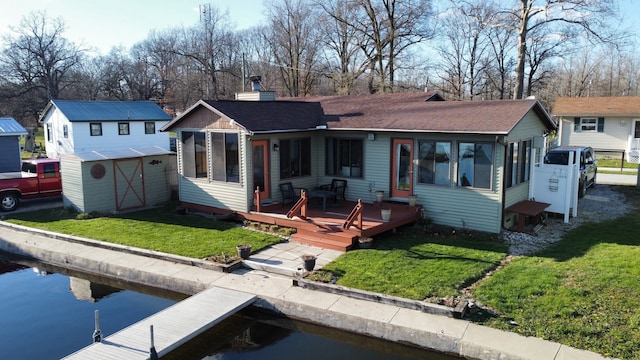 view of front of house with a deck with water view, a front lawn, and a shed