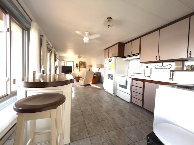 kitchen with white electric stove, dark tile floors, backsplash, a kitchen bar, and ceiling fan