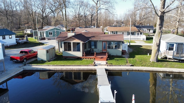 back of house featuring a yard, a deck with water view, and an outdoor structure