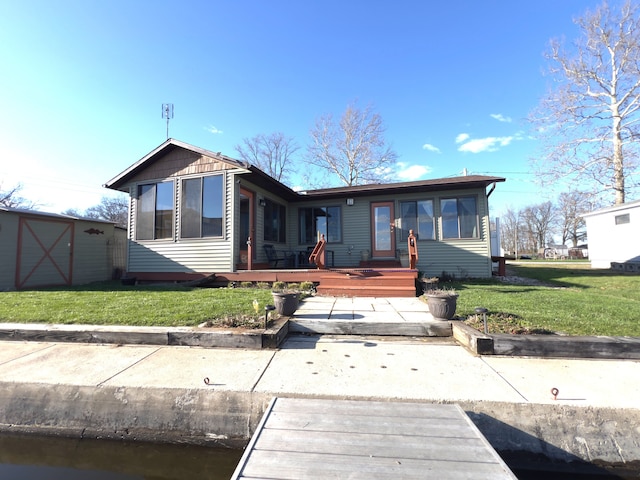 back of property featuring a deck, a storage shed, and a lawn