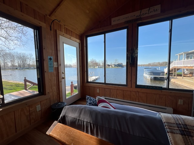 bedroom with wood walls, a water view, lofted ceiling, dark hardwood / wood-style floors, and a baseboard radiator