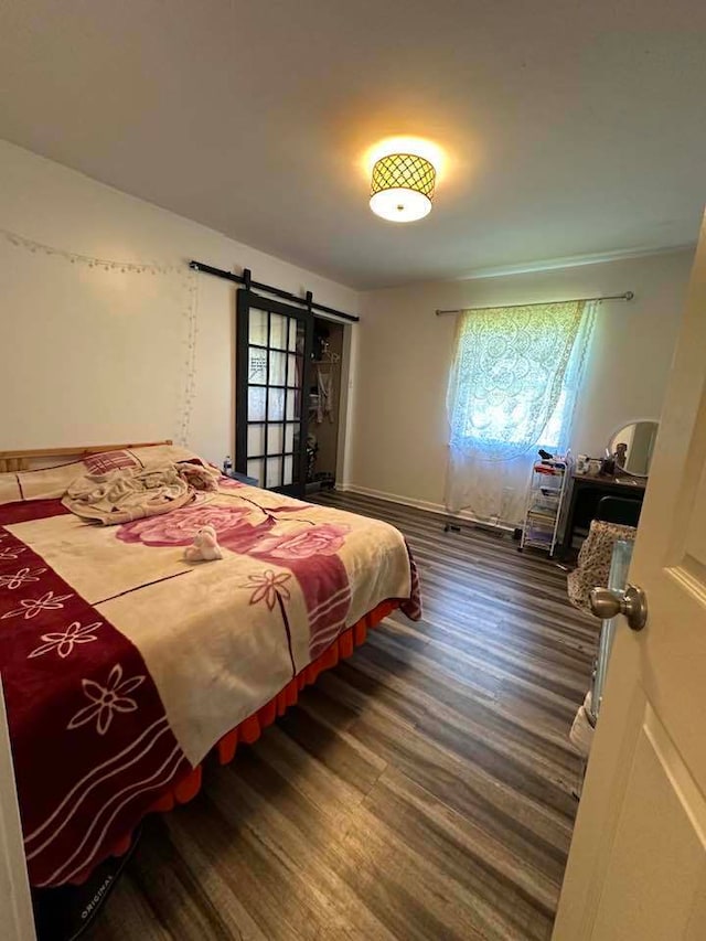 bedroom featuring dark hardwood / wood-style flooring and a barn door