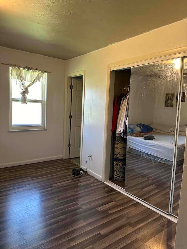 unfurnished bedroom with a closet and dark hardwood / wood-style floors