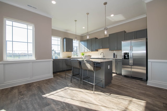 kitchen featuring gray cabinets, pendant lighting, a kitchen island, a kitchen bar, and stainless steel fridge with ice dispenser