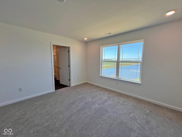 empty room with dark colored carpet and a water view