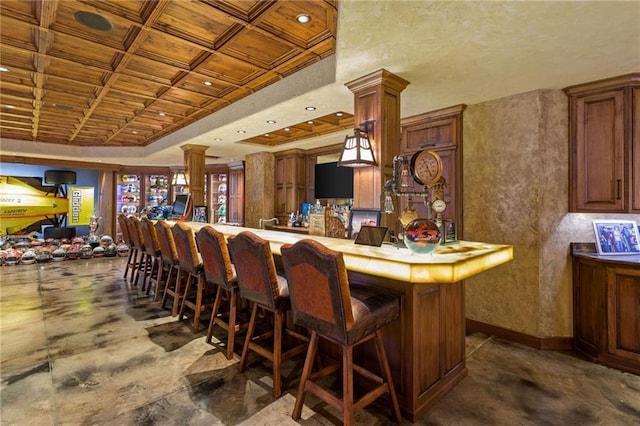 bar featuring coffered ceiling and ornate columns