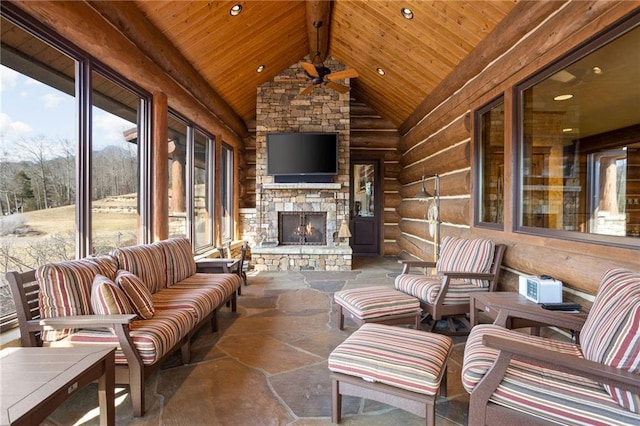 sunroom / solarium with vaulted ceiling with beams, ceiling fan, a fireplace, and wood ceiling