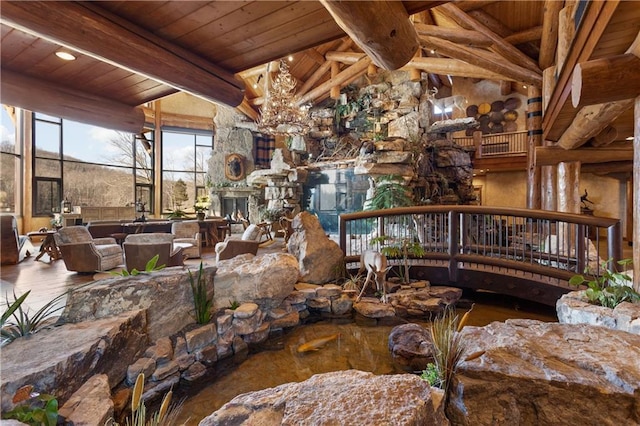 interior space featuring vaulted ceiling with beams, wooden ceiling, a fireplace, and an inviting chandelier