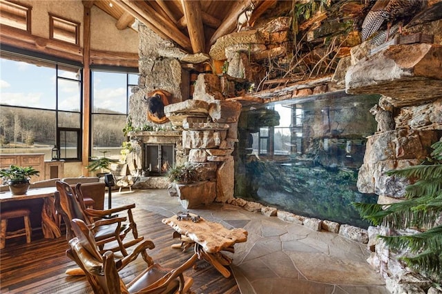 interior space with high vaulted ceiling, beam ceiling, a stone fireplace, and dark hardwood / wood-style floors