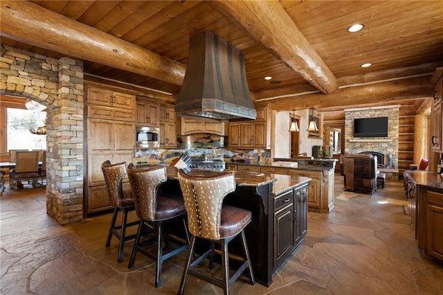 kitchen featuring a center island, ventilation hood, beam ceiling, and stainless steel microwave