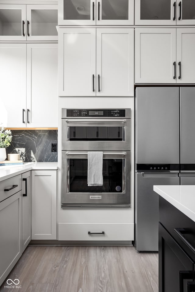 kitchen featuring stainless steel appliances, tasteful backsplash, white cabinets, and light hardwood / wood-style floors