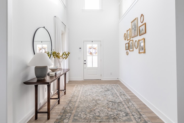 foyer entrance with light hardwood / wood-style flooring and a high ceiling