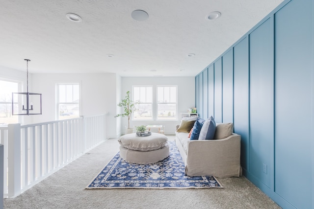 living area with a chandelier, carpet flooring, plenty of natural light, and a textured ceiling