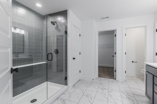 bathroom with a shower with door, vanity, toilet, and tile floors