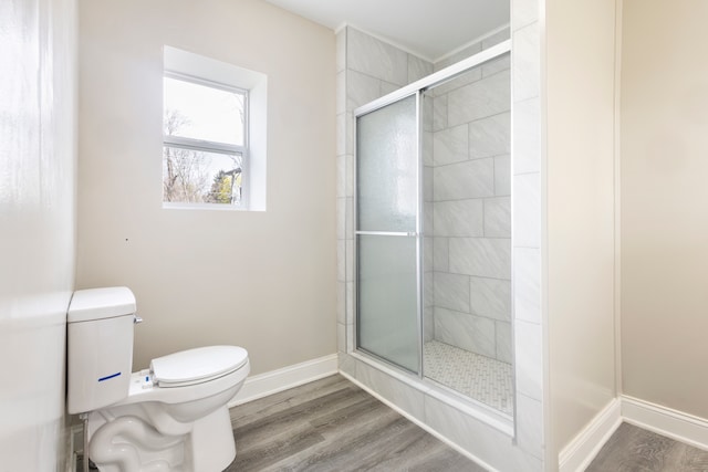 bathroom with hardwood / wood-style floors, toilet, and a shower with shower door