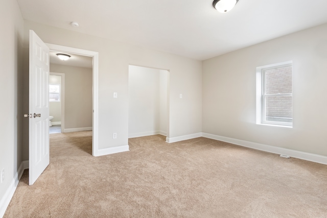 unfurnished bedroom featuring a closet and light carpet