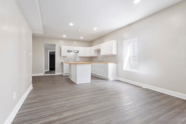 kitchen with white cabinetry, dark hardwood / wood-style floors, backsplash, sink, and a kitchen island