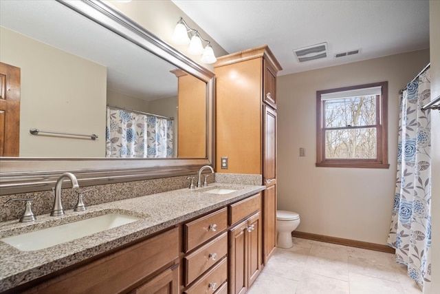 bathroom featuring dual vanity, tile patterned flooring, and toilet