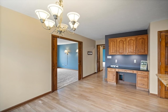 kitchen featuring an inviting chandelier, light stone countertops, built in desk, hanging light fixtures, and light carpet