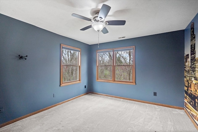 carpeted spare room featuring ceiling fan