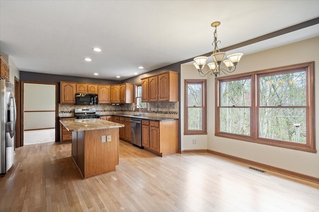 kitchen featuring light hardwood / wood-style floors, a wealth of natural light, pendant lighting, and stainless steel appliances