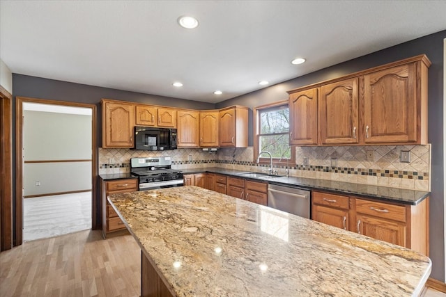 kitchen featuring sink, light stone counters, stainless steel appliances, and backsplash