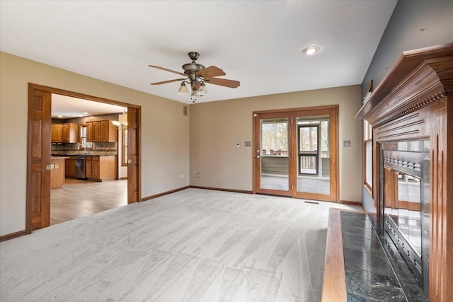 unfurnished living room featuring light carpet and ceiling fan