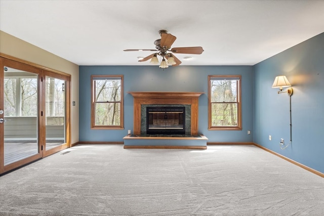 unfurnished living room with carpet floors, ceiling fan, and a wealth of natural light