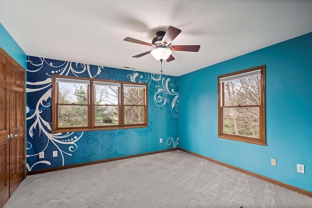 empty room featuring plenty of natural light, ceiling fan, and carpet flooring