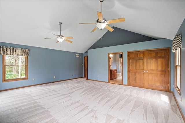 carpeted spare room with ceiling fan and high vaulted ceiling