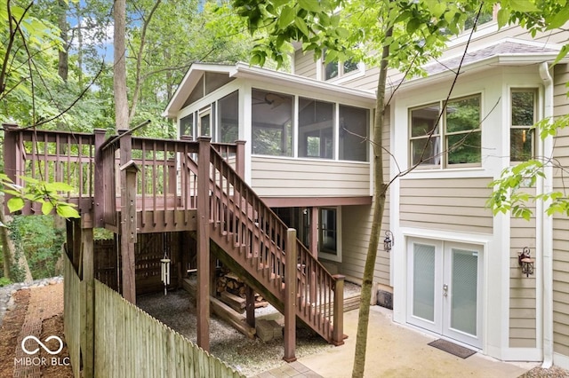 rear view of house featuring a sunroom, a wooden deck, and french doors