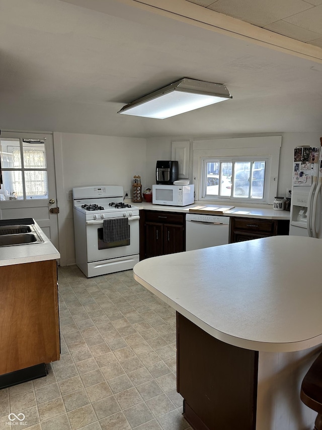 kitchen with a wealth of natural light, white appliances, light countertops, and a peninsula