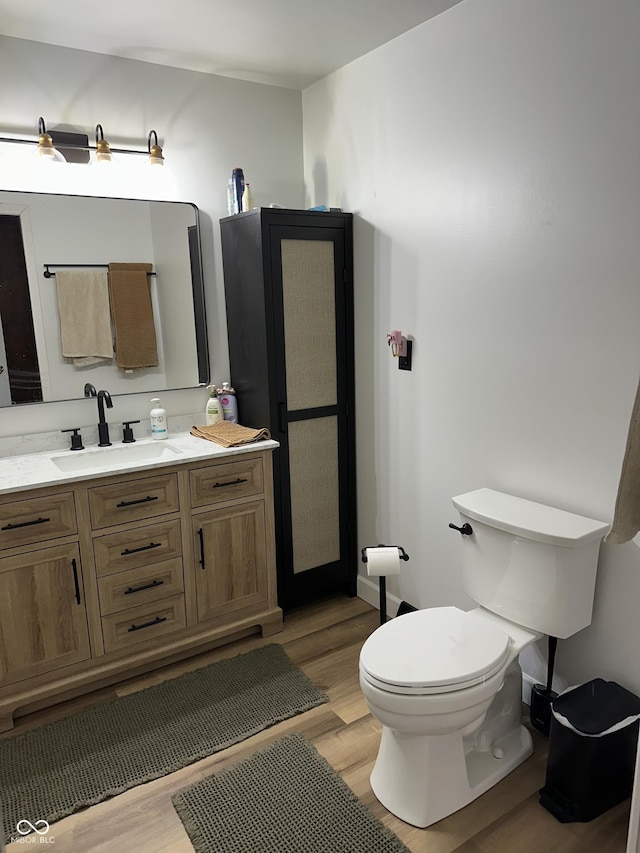 bathroom with toilet, wood finished floors, and vanity