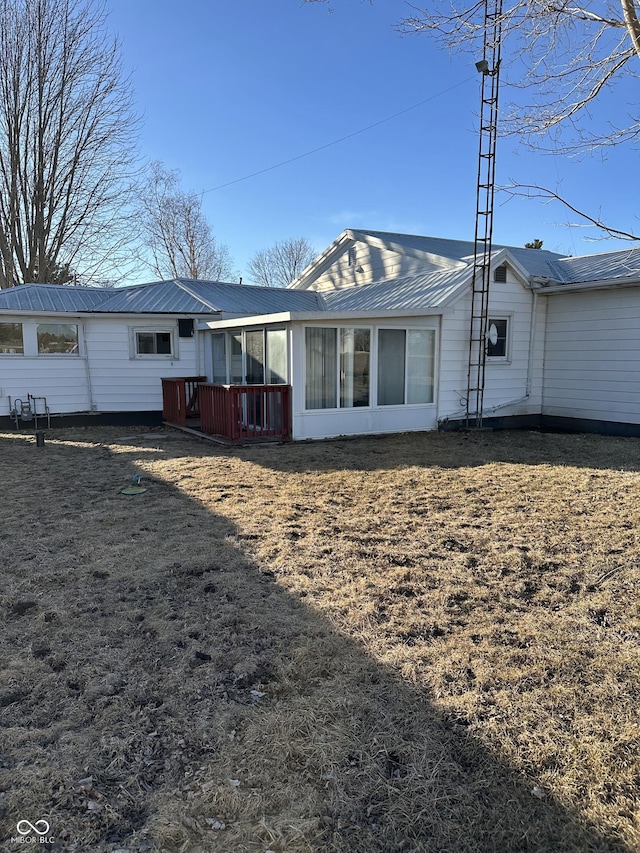 rear view of house featuring metal roof and a yard