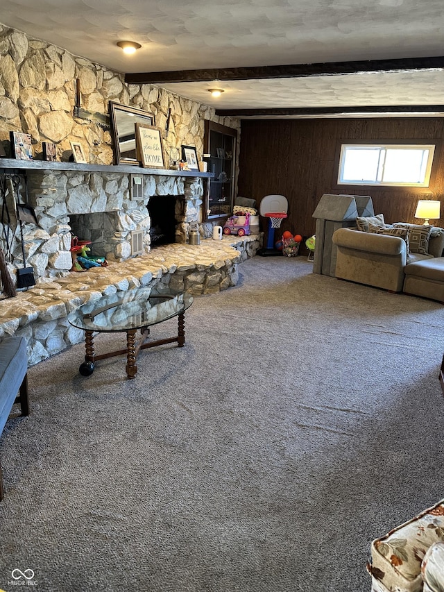 living room featuring wooden walls, carpet, beam ceiling, and a stone fireplace